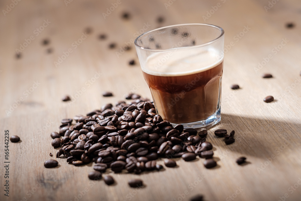 Fresh coffee in a glass with coffee beans on a wood table Fresh coffee in a glass with coffee beans on a wood table