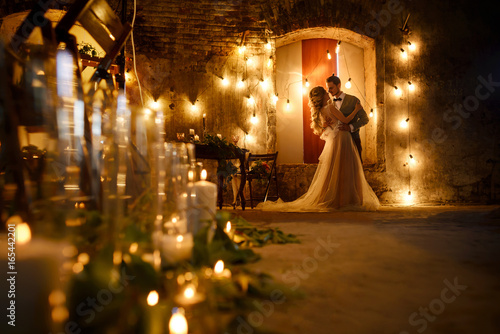 Leinwand Poster Stylish hipster wedding couple in romantic loft decorations at night