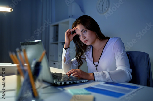businesswoman with laptop at night office