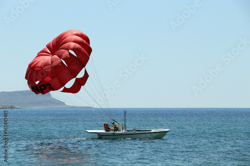 A Boat Pulls Colorful Para Sailing At The Blue Sea photo