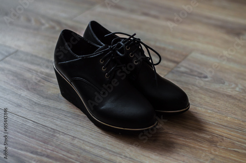 pair of women's black shoes with laces on wooden background