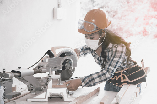 Asian pretty female carpenter using Electric Sander for wood photo