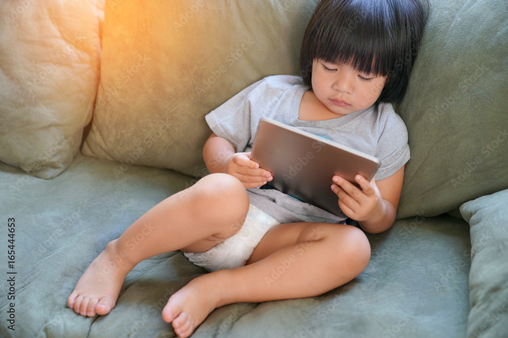 Portrait of child playing with digital tablet at home. Portrait of child playing with digital tablet at home.