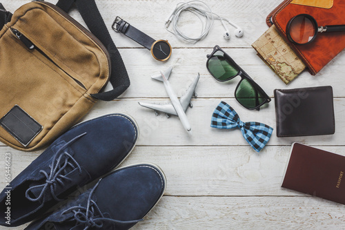 Top view accessories man fashion to travel concept.Airplane and earphone on wooden background.man's shoe,bag,bow tie,map,passport,watch,notebook on wood table.flat lay.copy space.