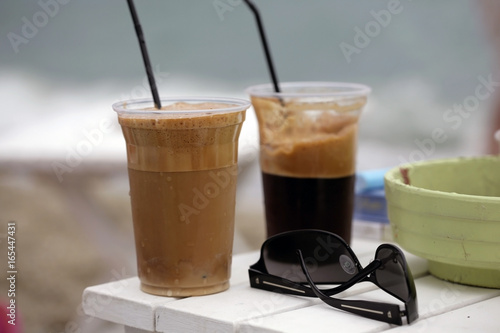 Two cups of coffee on white table on beach; close up, selective focus.