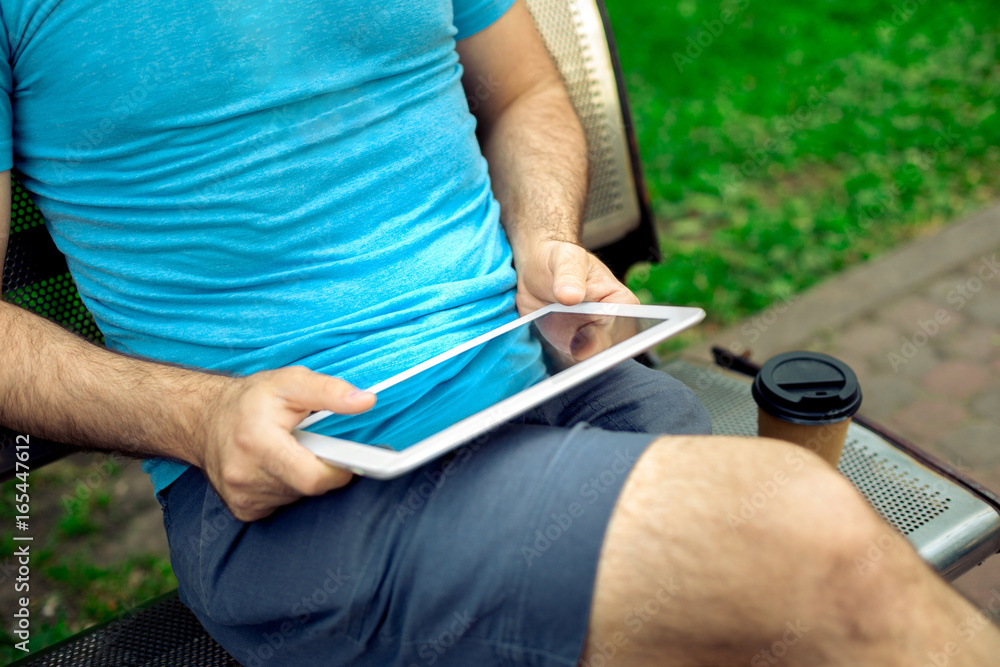Man sitting on a bench and using a digital tablet Man sitting on a bench and using a digital tablet