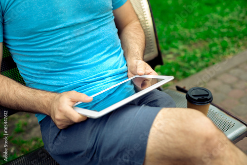 Man sitting on a bench and using a digital tablet