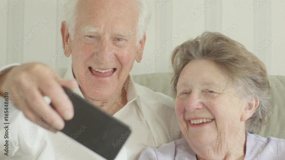 Happy Senior Caucasian couple taking selfies on a smartphone themes of smartphone technology selfie humour seniors Happy Senior Caucasian couple taking selfies on a smartphone themes of smartphone technology selfie humour seniors