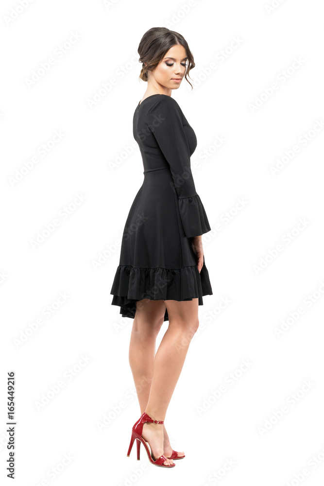 Sophisticated glamorous woman in black dress looking down. Side view. Full body length portrait isolated on white background. Sophisticated glamorous woman in black dress looking down. Side view. Full body length portrait isolated on white background.