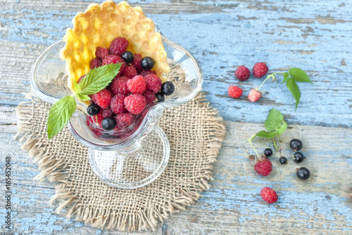 Fresh berries in glass bowl on wooden table