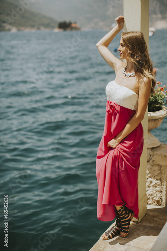 Young attractive woman in a dress relaxing by the sea