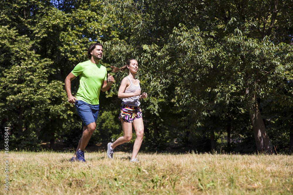 Young couple running in the park on a sunny day Young couple running in the park on a sunny day