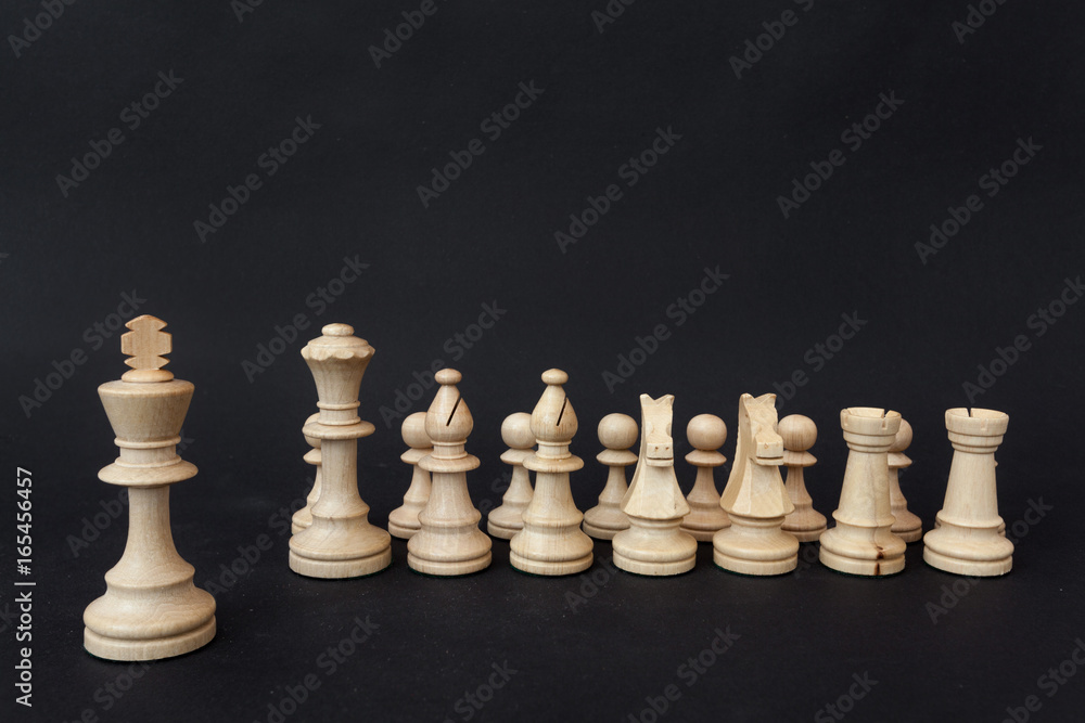 Army of wooden chess pieces led by the king on a dark background
