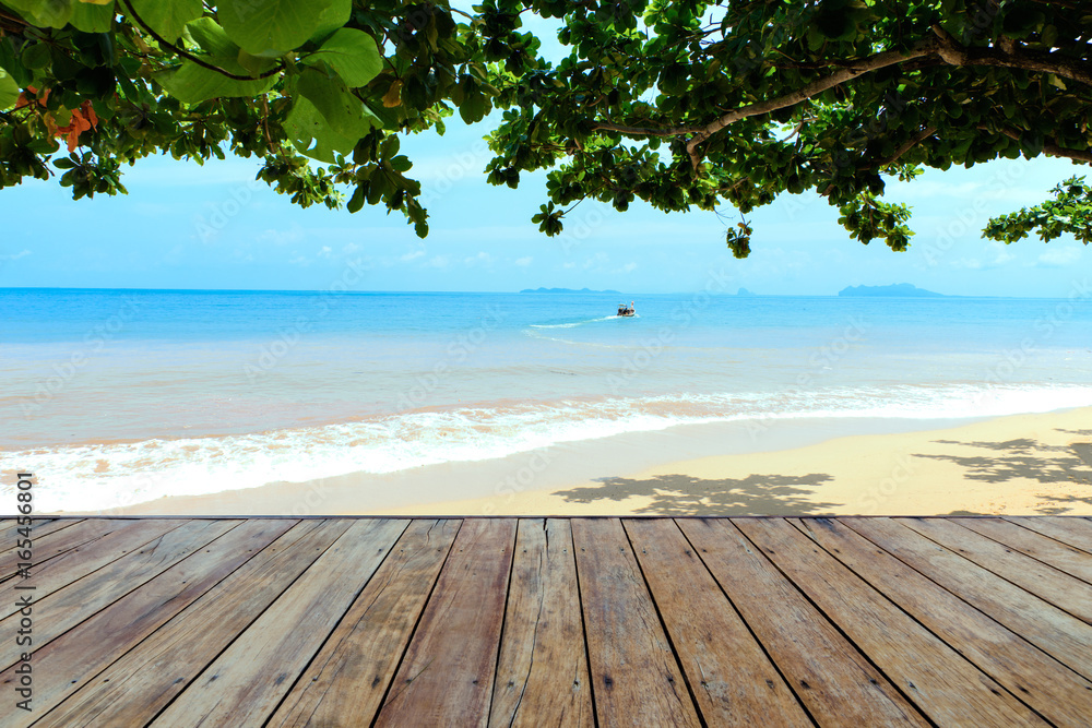 Fototapeta premium Top of the empty wooden floor under the shadow of the Indian almond tree on the sea-view background there is a boat, island and blue sky with clouds, product display concept