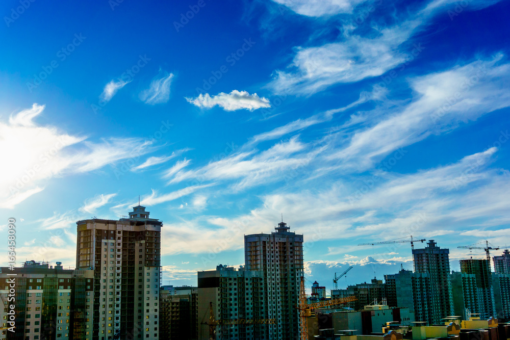 New modern buildings and cranes at dramatic sky background New modern buildings and cranes at dramatic sky background