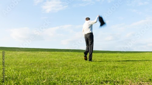 Carefree happy middle aged Caucasian businessman throwing off his jacket as he walks over a hill in celebration getting away from it all concept