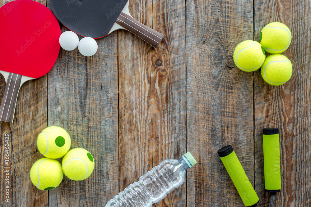 Sport background. Sport gear. Table tennis racket, tennis balls, hand expander on wooden background top view copyspace