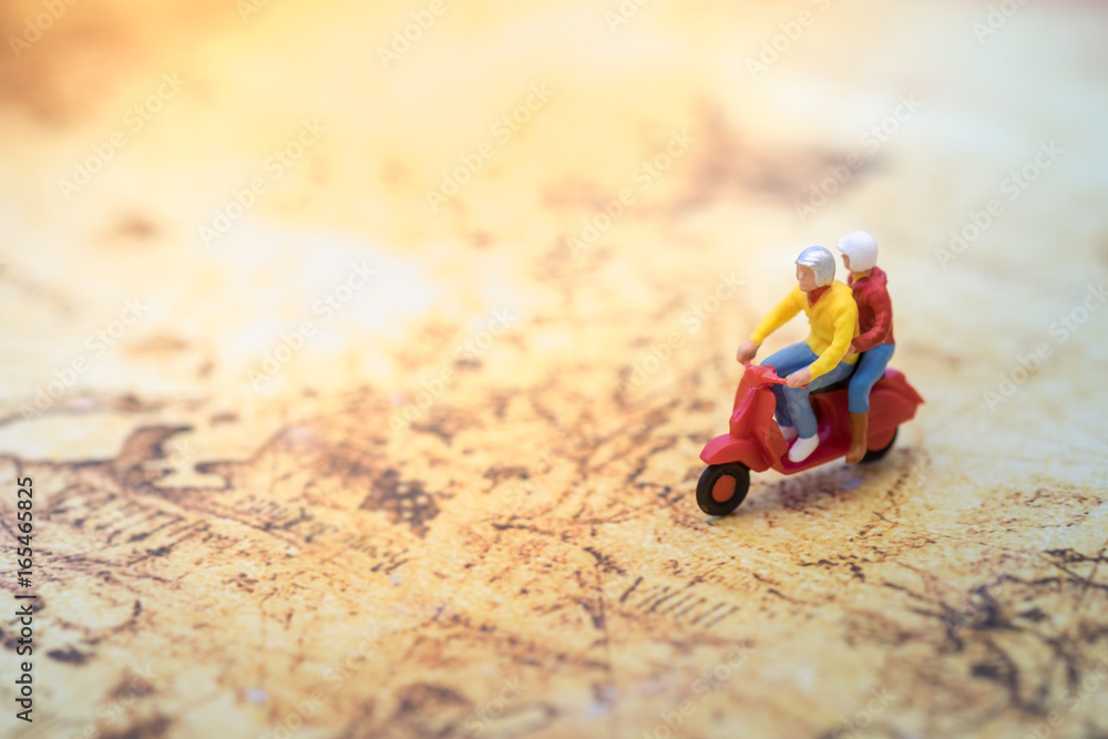 Travel Concept. Group of traveler miniature figures ride motorcycle / scooter on world map.