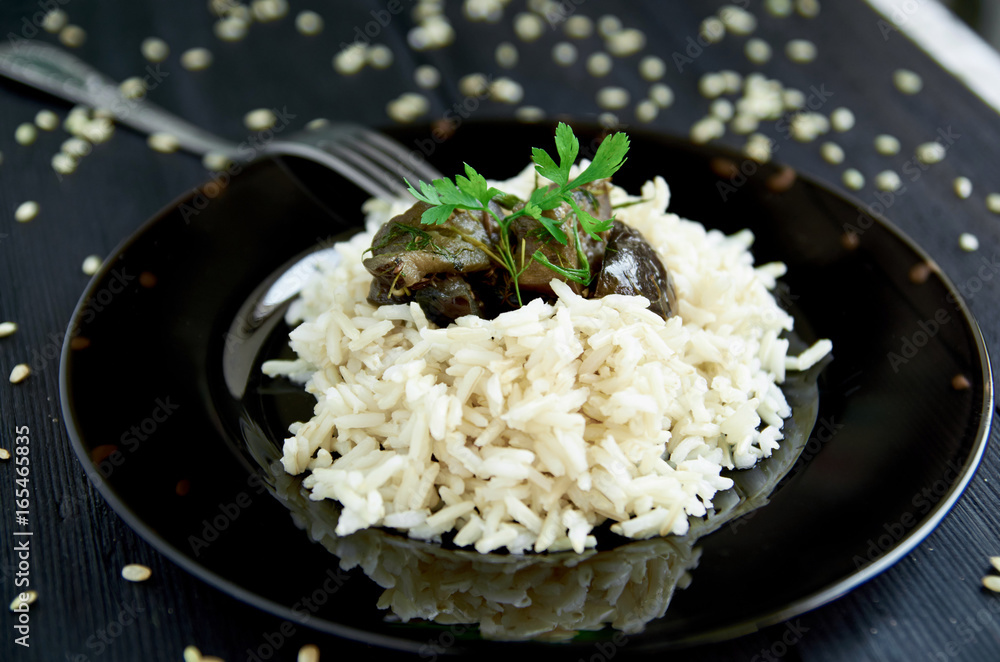 Boiled rice with stewed eggplants and fork decorated with herbs on a dark wooden background. Close up view Boiled rice with stewed eggplants and fork decorated with herbs on a dark wooden background. Close up view