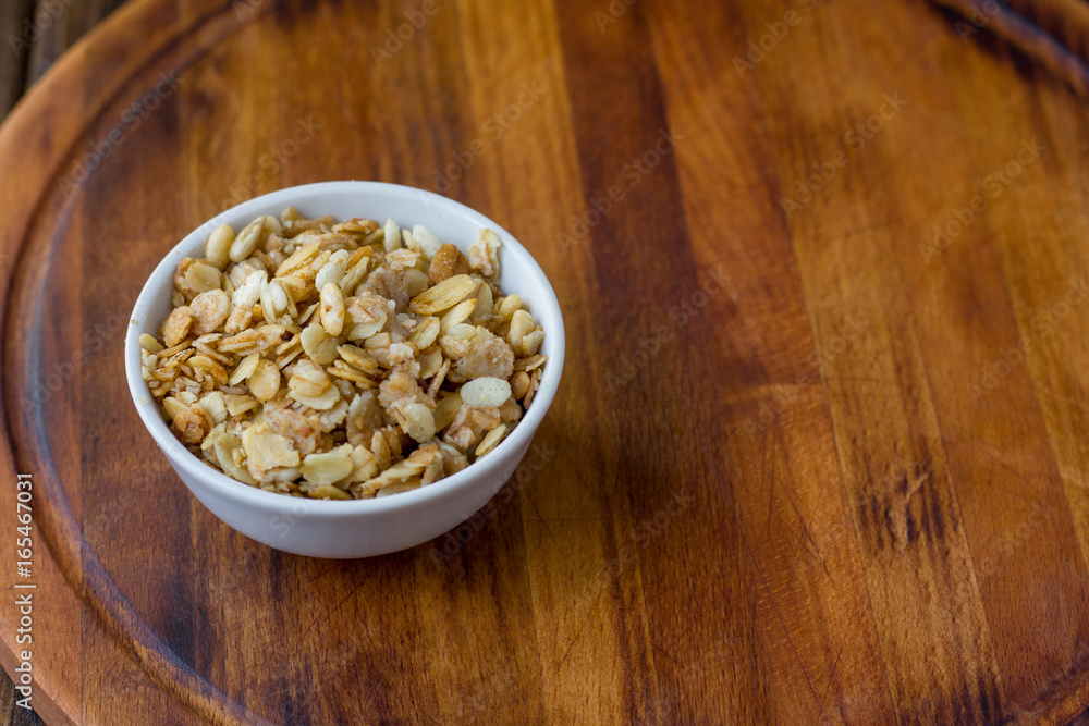Granola or muesli in white ceramic bowl over wooden table. Granola or muesli in white ceramic bowl over wooden table.
