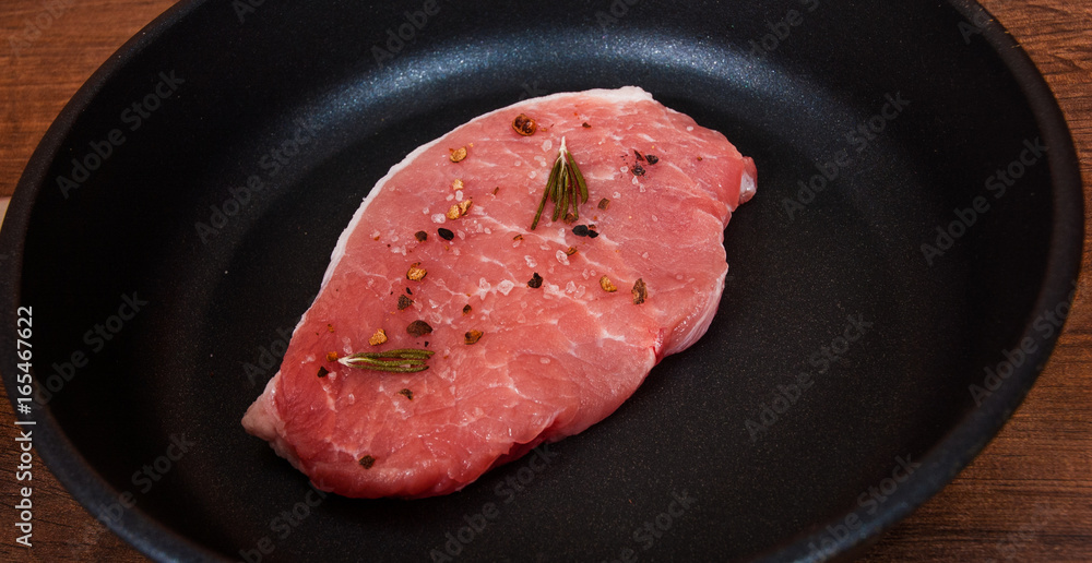 raw meat steak on cast iron frying pan on the brown wooden table background. raw meat steak on cast iron frying pan on the brown wooden table background.