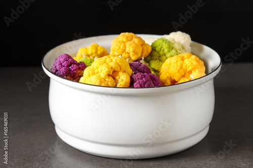 A rainbow of food. Purple cauliflower, orange cauliflower and broccoli, from the local market in London. Food for a vegan and a vegetarian. Dark background.