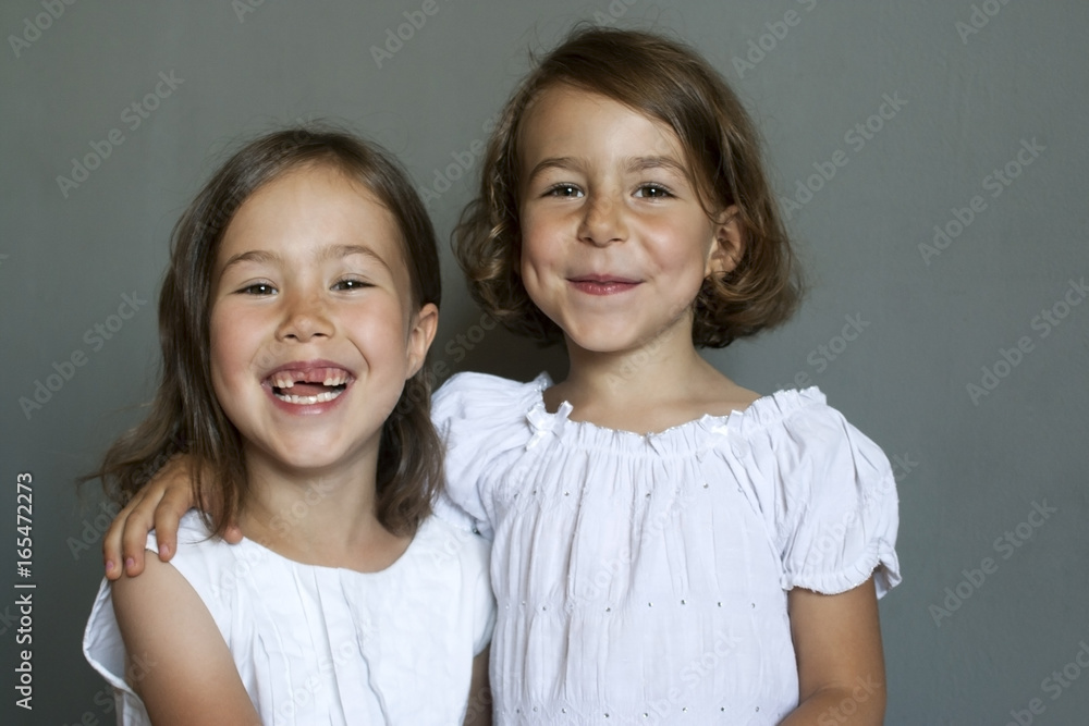 Portrait of two beautiful cheerful girls in white dresses. Good mood Portrait of two beautiful cheerful girls in white dresses. Good mood