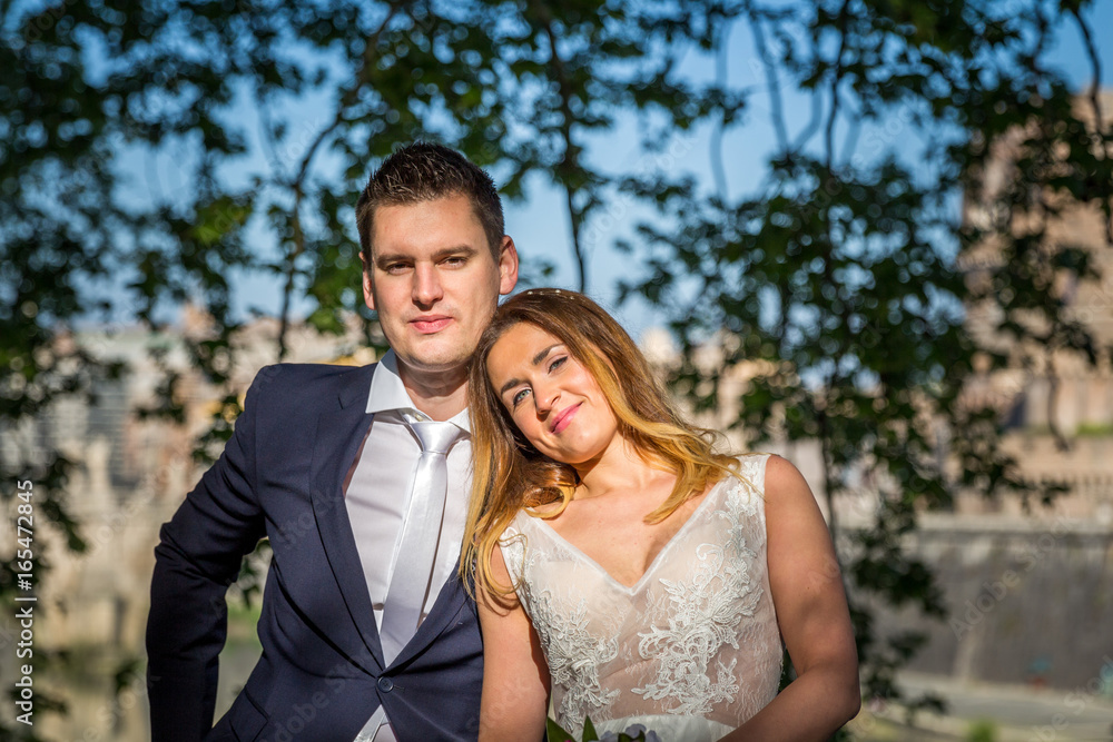 Bride and groom wedding poses under trees on the bank of the river Tiber, Rome, Italy Bride and groom wedding poses under trees on the bank of the river Tiber, Rome, Italy
