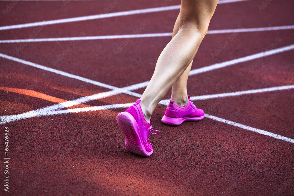 Close up on beautiful female legs with pink shoes on the running track