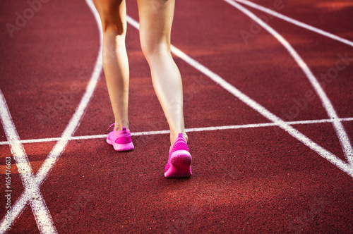 female athlete running in pink runners on a track 