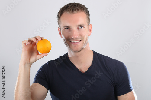 Bel homme tenant une orange dans sa main  © rdrgraphe