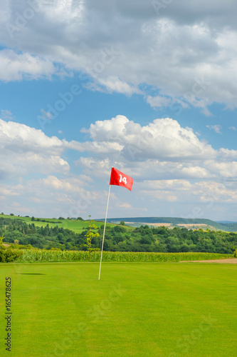 Golf field green grass red flag cloudy blue sky