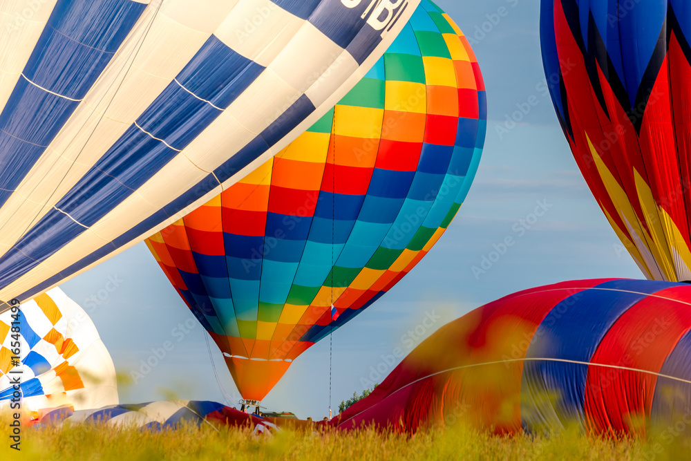 Obraz premium Colorful hot air balloons flying in the blue sky. The first minute after takeoff. Balloon Festival — The Golden Ring Of Russia — Pereslavl Zalesskiy.