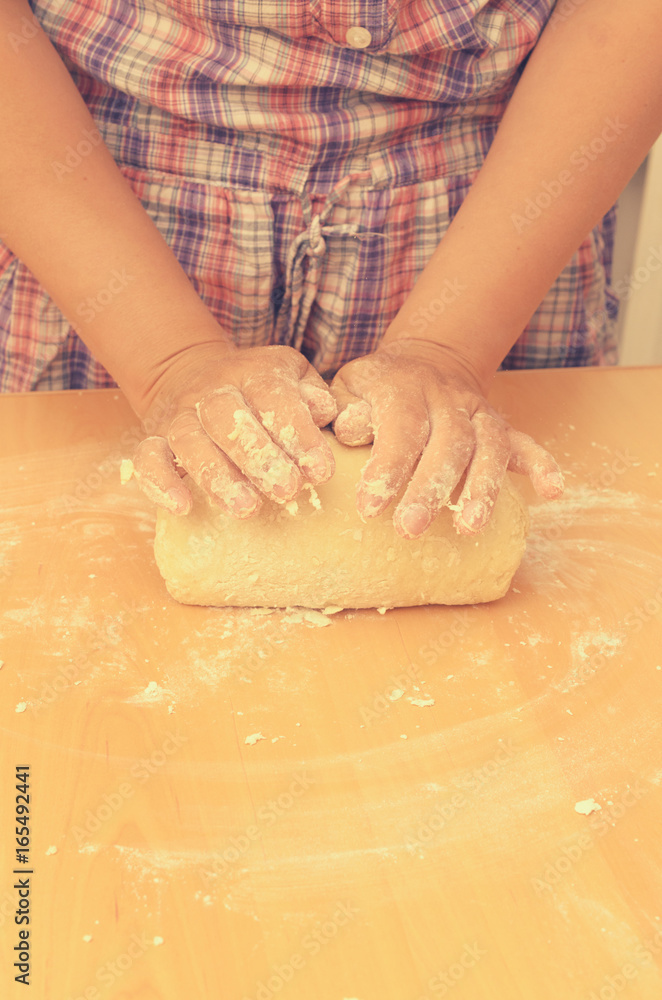 A woman kneads a homemade dough for pizza production.