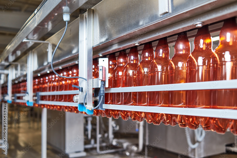 Plastic bottles for beer or carbonated beverage moving on conveyor