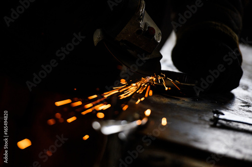 Metal grinding on steel pipe with flash of sparks close up
