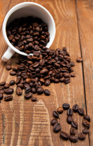 Overturned white cup with coffee beans