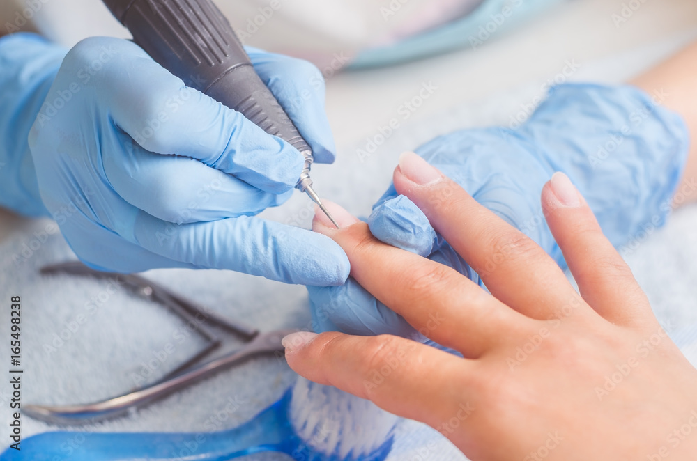 Master of manicure in rubber gloves makes a manicure with the help of a nail polish machine on the nails of a woman Master of manicure in rubber gloves makes a manicure with the help of a nail polish machine on the nails of a woman