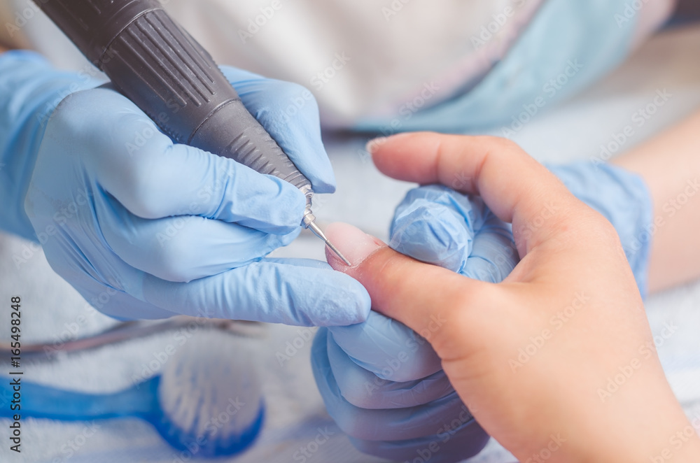Master of manicure in rubber gloves makes a manicure with the help of a nail polish machine on the nails of a woman Master of manicure in rubber gloves makes a manicure with the help of a nail polish machine on the nails of a woman
