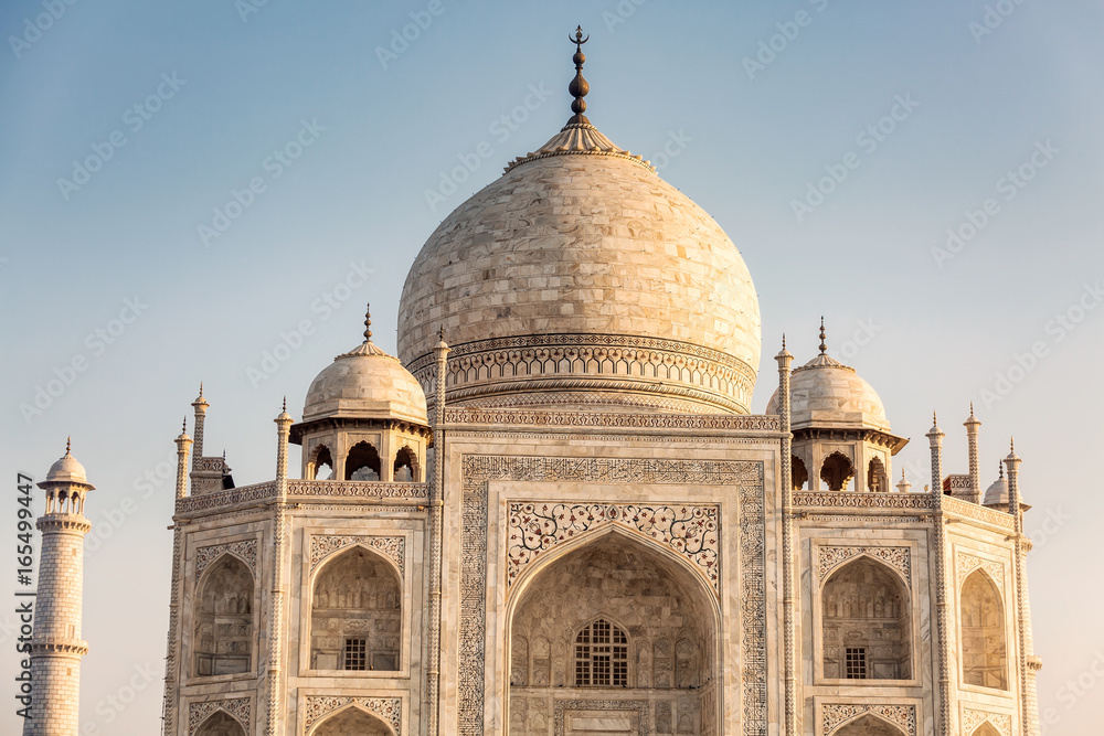 View of Taj Mahal with pool reflection in Agra India at sunrise.
