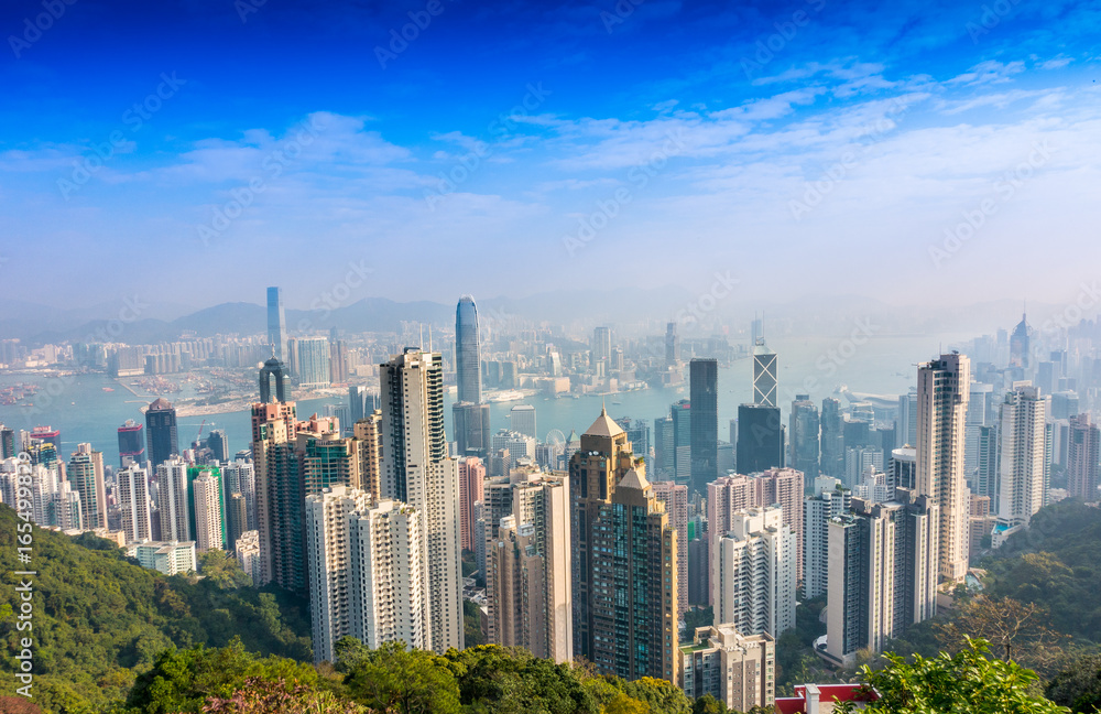 Fototapeta premium Beautiful view from Victoria Peak to the city of Hong Kong in the horizont in a sunny day with blue sky
