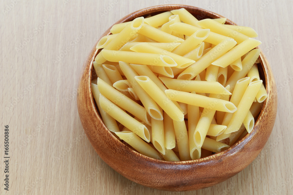 Raw Macaroni in the wooden bowl on wood background. Raw Macaroni in the wooden bowl on wood background.