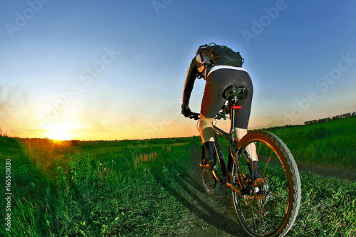 cyclist rides on the road into the sunset.