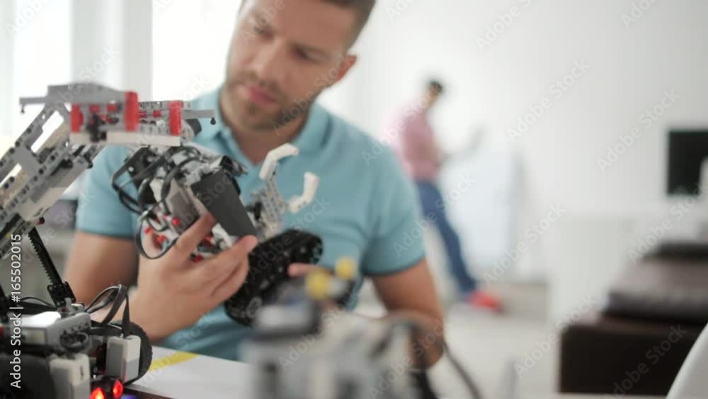 Man smiling while working on robotic machine Man smiling while working on robotic machine