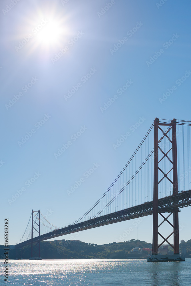 Lisbon 25 april suspension bridge againt blue sky and sun Lisbon 25 april suspension bridge againt blue sky and sun