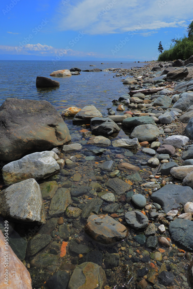 the shore of the lake with large stones in the summer