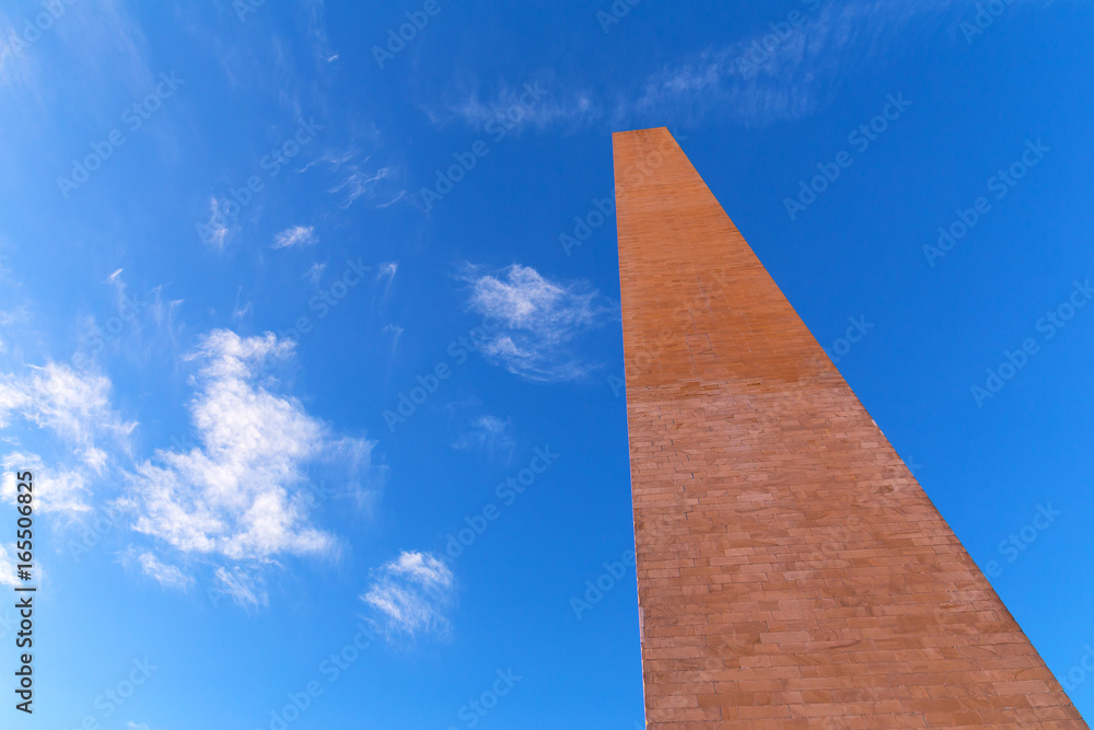 A top part of Washington Monument under the high blue sky. The famous obelisk of the USA is aimed high in the sky.