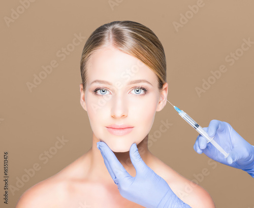 Young and beautiful woman having skin injections over brown background. Plastic surgery concept.