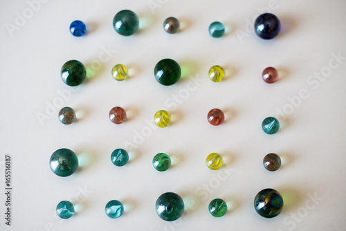 Glass marbles of different colours on a white plain table