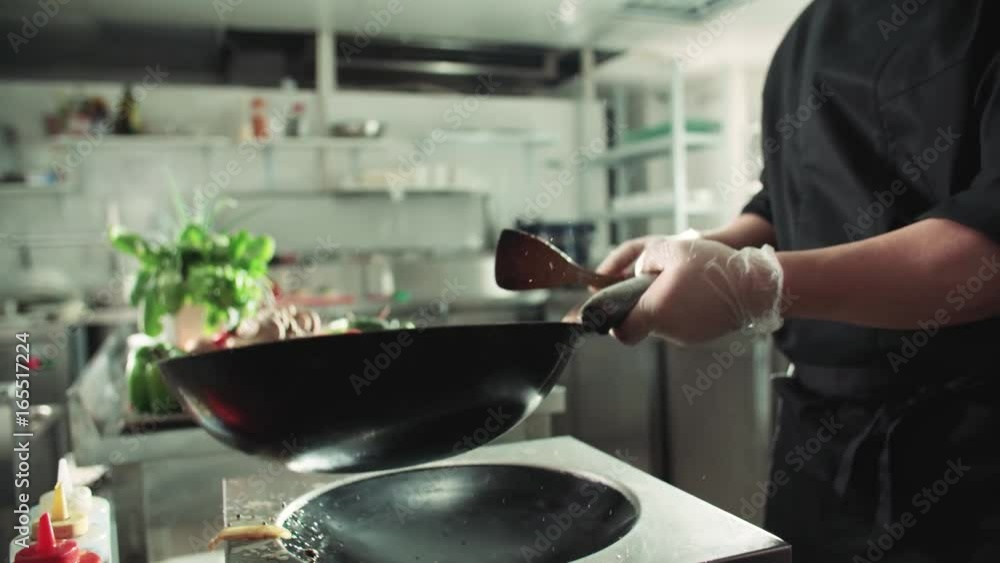 close-up of a chef working the wok with flames roasting mixed colorful vegetables tossing them , restaurant kitchen , slow motion close-up of a chef working the wok with flames roasting mixed colorful vegetables tossing them , restaurant kitchen , slow motion
